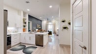 Located in Allen, TX, this thoughtfully designed 2-bedroom, 2-bathroom residence offers a seamless open-concept layout with modern finishes throughout. Light wood-tone flooring flows continuously across the entire floor, lending a bright and cohesive aesthetic to every room.

The kitchen is outfitted with crisp white shaker cabinetry, white quartz countertops, a subway tile backsplash, and a full suite of stainless steel appliances, including a French door refrigerator, electric range, microwave, and dishwasher. A peninsula with an undermount sink connects the kitchen directly to the living area, enhancing the open flow.

The living room features a striking navy accent wall, recessed lighting, a ceiling fan, and access to an outdoor balcony through floor-to-ceiling patterned drape panels, filling the space with natural light.

The spacious primary bedroom includes built-in shelving, recessed lighting, and a generous walk-in closet with multi-tiered hanging rods and shelving. Its en-suite bathroom offers a dual-sink vanity with a backlit mirror, a tiled walk-in shower, and direct closet access. The second bedroom features a warm terracotta accent wall and ample natural light. A second full bathroom with a glass-enclosed shower and lighted vanity mirror completes the layout.
