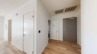This contemporary single-floor residence is defined by clean lines, an open layout, and an abundance of natural light. The expansive living area is anchored by large floor-to-ceiling windows and sliding glass doors that open onto a balcony, offering sweeping panoramic city views. Light wood-look flooring runs throughout the main living spaces, lending warmth and continuity to the design.

The galley-style kitchen is well-appointed with rich walnut-toned cabinetry extending to the ceiling, quartz countertops, a stainless steel refrigerator, range, and microwave, as well as a window above the sink that brings in additional natural light and urban views.

Both bedrooms are carpeted and generously proportioned, each featuring floor-to-ceiling windows that frame impressive cityscape vistas and allow sunlight to flood the rooms throughout the day.

The bathrooms are finished with modern touches, including wood-grain vanities with quartz countertops, large-format tile flooring, and soaking tubs with marble-style tiled surrounds that add a refined aesthetic.

A dedicated entryway provides a practical transition into the home, complete with an in-unit stacked washer and dryer, a smart thermostat, and a closet. The overall design balances functionality with a sophisticated, contemporary aesthetic throughout.