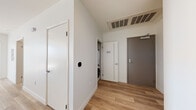 This contemporary single-floor residence is defined by clean lines, an open layout, and an abundance of natural light. The expansive living area is anchored by large floor-to-ceiling windows and sliding glass doors that open onto a balcony, offering sweeping panoramic city views. Light wood-look flooring runs throughout the main living spaces, lending warmth and continuity to the design.

The galley-style kitchen is well-appointed with rich walnut-toned cabinetry extending to the ceiling, quartz countertops, a stainless steel refrigerator, range, and microwave, as well as a window above the sink that brings in additional natural light and urban views.

Both bedrooms are carpeted and generously proportioned, each featuring floor-to-ceiling windows that frame impressive cityscape vistas and allow sunlight to flood the rooms throughout the day.

The bathrooms are finished with modern touches, including wood-grain vanities with quartz countertops, large-format tile flooring, and soaking tubs with marble-style tiled surrounds that add a refined aesthetic.

A dedicated entryway provides a practical transition into the home, complete with an in-unit stacked washer and dryer, a smart thermostat, and a closet. The overall design balances functionality with a sophisticated, contemporary aesthetic throughout.