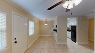 This two-story townhouse offers a practical and comfortable layout across two floors, featuring 2 bedrooms and 1.5 bathrooms. The main level showcases light tile flooring throughout the open living and dining area, which is finished with crown molding and ceiling fans for added comfort. A pendant light fixture over the dining space adds a subtle decorative touch, while natural light filters in through slatted blinds on the windows. The kitchen is well-appointed with white cabinetry, dark countertops, a black electric range with coil burners, an over-the-range microwave, and a black refrigerator—providing all essential appliances in a clean, functional space. A convenient half bathroom is located on the main floor, featuring tile flooring and a dark-finished vanity. Upstairs, both bedrooms are generously sized, each outfitted with plush wall-to-wall carpeting, ceiling fans with light kits, and windows with blinds that allow for natural light. The full bathroom features large-format tile on both the floors and tub surround, a soaking tub with shower, a dark wood vanity, and oil-rubbed bronze fixtures, creating a cohesive and polished look. The overall ambiance of the townhouse is clean, neutral, and move-in ready.