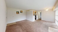Located at 3542 Dean Dr in Hyattsville, Maryland, this single-floor residence offers a well-organized and functional layout designed for comfortable everyday living. The expansive living area is finished with warm, wall-to-wall carpeting and neutral-toned walls that create a bright, inviting atmosphere. Large sliding glass doors and wide windows line one wall of the living space, flooding the interior with generous natural light and providing views of the surrounding greenery. A ceiling fan adds both style and practicality to the room. The kitchen is designed in a classic galley configuration, featuring warm wood cabinetry, a mosaic tile backsplash in earthy tones, laminate countertops, and a full suite of black appliances including a gas range, refrigerator, and dishwasher. Light tile flooring completes the kitchen's clean, functional aesthetic. A half-wall with glass panel details connects the kitchen to the living area, maintaining an open feel while defining each space. A separate bedroom offers plush carpeting and clean white walls, providing a quiet and restful retreat. The bathroom includes a tub-shower combination. Throughout the residence, the design emphasizes simplicity, practicality, and ease of living in a well-maintained single-level setting.