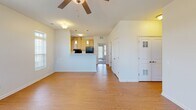Located at 184 Sandbar Ct NE in Rochester, Minnesota, this single-floor residence offers a thoughtfully laid-out interior with a clean, neutral aesthetic throughout. The open-concept living area greets you at entry, featuring warm hardwood-style flooring, a ceiling fan, and multiple large windows with blinds that invite generous natural light. A transom-topped front door is flanked by wide windows, creating a bright and welcoming entryway. The living space flows seamlessly into a raised breakfast bar that connects to the galley-style kitchen, which is outfitted with light wood cabinetry, ample counter space, a full suite of appliances including a refrigerator, range, dishwasher, and microwave, and a window above the cooking area providing additional daylight. A dedicated carpeted room with a ceiling fan and a private exterior door offers flexibility as a bedroom or additional living space, complete with access to outdoor views. The bathroom features a dual-sink vanity with light wood cabinetry, mirrored medicine cabinets, and clean white countertops, with a direct sightline into the kitchen corridor. The consistent use of hardwood-style flooring and soft neutral wall tones throughout creates a cohesive, move-in-ready environment well-suited for comfortable everyday living.