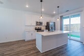 This two-story home offers a clean, contemporary design with a cohesive neutral palette and modern finishes throughout. The kitchen serves as a standout feature on the main level, showcasing floor-to-ceiling white shaker cabinetry, light quartz countertops, and a full suite of stainless steel appliances including a side-by-side refrigerator, electric range with microwave, and a deep undermount sink set into a central island. Warm-toned pendant lighting hangs above the island, complementing the wood-look luxury vinyl plank flooring that runs throughout the main level. A sliding glass door at the end of the kitchen provides direct access to an outdoor fenced area, filling the space with natural light.

The upper level features carpeted bedrooms with neutral walls, ceiling fans, and windows that bring in ample daylight with views of the surrounding neighborhood. The primary bathroom is well-appointed with a white vanity, quartz countertop, industrial-style sconce lighting, and a glass-enclosed walk-in shower with wood-look flooring. A secondary full bathroom includes a single vanity and a tub-shower combination. A convenient half bath with a pedestal sink is located on the main level.