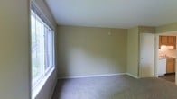This multi-floor property spans three levels, offering a versatile layout across its floors. The pictured room showcases a clean, minimalist interior with warm beige walls that create a neutral and welcoming atmosphere. Soft, neutral-toned carpet covers the floor, adding a layer of comfort underfoot. A large window along one wall allows generous natural light to fill the space, illuminating the room and providing views of the surrounding greenery outside. White baseboards provide a crisp contrast against the warm wall color, contributing to the room's tidy, well-maintained appearance. The smooth white ceiling completes the space with a clean finish. The room's simple design offers a blank canvas, making it highly adaptable for a variety of uses. With three floors in total, the property provides ample space distributed across multiple levels, allowing for flexible use of each floor. The overall ambiance of the space is calm and understated, with an emphasis on natural light and neutral tones that create a bright, livable environment throughout.