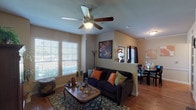 Located in Conroe, TX, this single-story home offers a thoughtfully designed layout that balances comfort and functionality. The open-concept living and dining area is anchored by warm hardwood flooring, a ceiling fan, and large windows with blinds that invite generous natural light and views of the surrounding greenery. A low half-wall with an arched pass-through separates the living space from the kitchen, maintaining an airy, connected feel throughout.

The kitchen is well-equipped with rich wood cabinetry, granite countertops, a breakfast bar, and black appliances including a range, microwave, and dishwasher. The adjoining dining area features a window with full-length drapes, creating an intimate setting for meals.

The two bedrooms are carpeted for comfort and each includes a ceiling fan and window with natural light. Both rooms feature sleigh-style bed frames and offer a cozy, restful atmosphere, with one bedroom providing additional closet access.

The bathroom is generously sized, showcasing a wide granite vanity, wood cabinetry, a large mirror with overhead lighting, a soaking tub, and a separate shower area — all finished with tile flooring and warm neutral tones. The overall ambiance of the home is warm and inviting, with consistent earth-toned décor throughout.