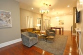 Located at 145 Granby Street in Norfolk, Virginia, this single-floor space offers a sophisticated and well-appointed interior with a cohesive modern aesthetic. Rich hardwood flooring runs throughout, anchoring the warm yet refined atmosphere found in every area of the space.

The kitchen is outfitted with white shaker cabinetry, marble-look countertops, a grey subway tile backsplash, and stainless steel appliances including a range with a wall-mounted hood. A peninsula with seating provides a casual dining or gathering option, making the kitchen both functional and welcoming.

The main living and entertainment area is expansive and thoughtfully arranged. A textured geometric accent wall serves as a striking focal point, flanked by built-in shelving and a sleek fireplace. A wall-mounted television sits above the fireplace, while stylish pendant and chandelier lighting illuminate the space. Comfortable seating arrangements define distinct lounge zones, and a full-size billiards table with a statement chandelier overhead adds a recreational dimension. A raised platform area offers additional flexible seating. The overall ambiance is modern and upscale, ideal for gathering and entertaining.