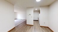 This 2-bedroom, 1-bathroom unit is thoughtfully laid out across a single floor, offering a comfortable and efficient use of space. The combined kitchen and living area serves as the heart of the home, with the kitchen featuring warm oak cabinetry, white countertops, and wood-look vinyl flooring, while the adjacent living room transitions to plush carpeting and includes a sliding glass door that opens to an outdoor balcony area, allowing for natural light and outdoor views. A wall-mounted air conditioning unit and baseboard heating are present throughout, ensuring year-round comfort. The textured ceilings are consistent across the unit, lending a cohesive feel to each room. The primary bedroom is a well-proportioned retreat with carpet flooring, baseboard heating, and a double-door closet providing ample storage. The second bedroom mirrors this layout, featuring a framed window with blinds and the same soft carpeting. The full bathroom is clean and straightforward, offering a shower-tub combination, wood-vanity with countertop, and wood-look flooring. Overall, the unit presents a practical and comfortable living space with warm wood tones and a neutral color palette throughout.