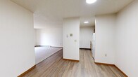 This 2-bedroom, 1-bathroom unit is thoughtfully laid out across a single floor, offering a comfortable and efficient use of space. The combined kitchen and living area serves as the heart of the home, with the kitchen featuring warm oak cabinetry, white countertops, and wood-look vinyl flooring, while the adjacent living room transitions to plush carpeting and includes a sliding glass door that opens to an outdoor balcony area, allowing for natural light and outdoor views. A wall-mounted air conditioning unit and baseboard heating are present throughout, ensuring year-round comfort. The textured ceilings are consistent across the unit, lending a cohesive feel to each room. The primary bedroom is a well-proportioned retreat with carpet flooring, baseboard heating, and a double-door closet providing ample storage. The second bedroom mirrors this layout, featuring a framed window with blinds and the same soft carpeting. The full bathroom is clean and straightforward, offering a shower-tub combination, wood-vanity with countertop, and wood-look flooring. Overall, the unit presents a practical and comfortable living space with warm wood tones and a neutral color palette throughout.