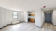 Located at 1930 Marion St in Columbia, SC, this one-bedroom, one-bathroom unit offers a clean, modern design across a single floor. The open living area features light wood-look luxury vinyl flooring, crisp white walls with dark baseboards, and a large black-framed window that brings in natural light and outdoor views. A wall-mounted PTAC unit provides individual climate control. The kitchen is efficiently integrated into the living space, equipped with warm wood-toned cabinetry, a stainless steel oven, a built-in microwave, a dishwasher, and a single-basin sink — all neatly arranged along one wall. The bedroom is a well-proportioned, private retreat with its own black-framed window, a baseboard heating unit, and recessed lighting. A dedicated closet area off the bedroom features built-in shelving and a hanging rod for organized storage. The bathroom is finished with neutral tile flooring, a white vanity with cabinet storage and a mirrored medicine cabinet, a standard toilet, and a shower/tub combination. Throughout the unit, the design emphasizes clean lines, neutral tones, and functional efficiency, making it a practical and comfortable living space.