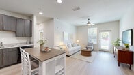 Located at 8300 Merrill Rd in Jacksonville, FL, this single-floor, 2-bedroom, 2-bathroom residence offers a thoughtfully designed open-concept layout with a clean, modern aesthetic. Light wood-style flooring flows through the main living areas, complemented by crisp white walls, recessed lighting, and ceiling fans throughout.

The combined kitchen and living room forms the heart of the home. The kitchen features dark espresso cabinetry, black appliances, granite-style countertops, and a freestanding island with seating — ideal for casual dining. The living area is generously proportioned, bathed in natural light from large windows and a glass door that opens to the outdoors.

Both bedrooms are carpeted and well-lit, each with ceiling fans and access to closet space. The primary bedroom is comfortably sized and connects to a dedicated bathroom and a spacious walk-in closet with wire shelving. The bathrooms feature dark vanity cabinetry with granite countertops, light flooring, and a shower-tub combination.

A dedicated laundry room with washer/dryer hookups adds everyday convenience, while two closets provide ample storage. The overall ambiance is bright, clean, and move-in ready, with a neutral palette that suits a variety of interior styles.