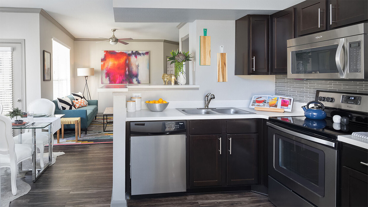 Cocina del apartamento con electrodomésticos de acero inoxidable, comedor y sala de estar con pisos de madera. - Griffis SoCo Austin