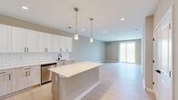Located at 1 Haddon Blvd in Mount Laurel, NJ, this one-bedroom, two-bathroom residence offers a thoughtfully designed layout with modern finishes throughout. Light hardwood-style flooring flows seamlessly across the single floor, complementing the warm neutral wall tones found in every room.

The open-concept kitchen is a standout feature, equipped with a center island, stainless steel appliances including a refrigerator, range, microwave, and dishwasher, white shaker-style upper cabinets, light wood lower cabinets with matte black hardware, and a classic white subway tile backsplash with white quartz countertops. Pendant lighting above the island adds a refined touch.

The spacious living area benefits from natural light and direct access to a private balcony through a sliding glass door, offering outdoor views. The generously sized primary bedroom features a wide window arrangement that invites additional natural light and connects to a private en-suite bathroom complete with a walk-in glass-enclosed shower with matte black framing. A second bathroom echoes the same contemporary aesthetic, featuring a light wood vanity, white quartz countertop, undermount sink, and matte black fixtures throughout.