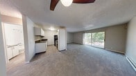 Located at 4455 NE 12th St in Renton, WA, this single-floor, 2-bedroom, 1-bathroom residence offers a well-organized layout with comfortable living spaces throughout. The living room is generously sized, featuring soft grey carpeting, a textured ceiling, and a sliding glass door that opens to a private balcony with views of surrounding greenery — filling the room with natural light and a connection to the outdoors. A baseboard heating system is present throughout the home, ensuring year-round comfort. The two bedrooms are carpeted and feature neutral grey-toned walls, textured ceilings, and windows that invite natural light. The primary bedroom is notably spacious, while the second bedroom includes a built-in closet and a convenient in-unit stacked washer and dryer tucked behind sliding doors — a practical feature that adds everyday ease. The bathroom is cleanly finished with wood-look luxury vinyl flooring, white cabinetry with modern hardware, a dark countertop, and a full tub/shower combination with a white surround. The kitchen connects directly to the main living area, contributing to an open and functional floor plan. Throughout the residence, the consistent use of neutral tones and carpet creates a cohesive and understated aesthetic well-suited for comfortable everyday living.
