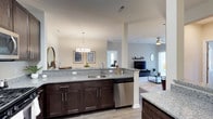 This single-floor residence at Gabrielle Run in Saddlebred offers a thoughtfully designed open-concept layout that seamlessly connects the kitchen, dining, and living areas. The kitchen is a standout feature, equipped with dark espresso cabinetry, granite countertops, stainless steel appliances including a gas range, microwave, refrigerator, and dishwasher, all set over light hardwood-style flooring. An in-unit stacked washer and dryer adds everyday convenience. The dining area is defined by an elegant pendant light fixture and flows naturally into the living room, which features a ceiling fan, large sliding glass doors that invite natural light, and access to an outdoor area. The primary bedroom offers a serene retreat with a ceiling fan and ample natural light, while additional bedrooms are equally comfortable with plush carpeting and generous window coverage. The primary bathroom is generously sized, featuring dual vanities with granite countertops, dark cabinetry, a soaking tub, and a separate glass-enclosed shower set on crisp tile flooring. A secondary full bathroom mirrors the same refined finishes with granite countertops and tile flooring. The overall ambiance throughout the residence is modern, clean, and cohesive.