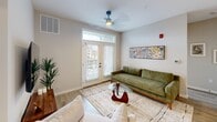 Located at 845 Greenfield Rd in Lancaster, PA, this well-appointed 2-bedroom, 2-bathroom residence offers a thoughtfully designed single-level floor plan with a clean, contemporary aesthetic throughout. The open-concept kitchen and living area serves as the heart of the home, featuring a large center island with bar seating, white flat-panel cabinetry, stainless steel appliances, subway tile backsplash, and bold pendant lighting — all set atop warm wood-look flooring. The living room opens to the outdoors through a glass-paneled door with transom window, inviting generous natural light and views of the surrounding community. Both bedrooms are carpeted and equipped with ceiling fans, offering a comfortable retreat. The spacious primary bedroom features large windows with expansive outdoor views. Each bathroom is finished with modern fixtures, including matte black hardware. The primary bath showcases a floating white vanity, glass-enclosed shower, and light tile flooring. The second bath features a light blue floating vanity with a framed mirror and white countertop. Clean lines, neutral tones, and consistent modern detailing create a cohesive and functional living environment throughout the entire space.