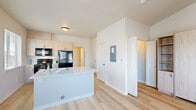Located at 2700 Pierce Pkwy in Springfield, Oregon, this efficiently designed single-floor unit offers a thoughtful layout comprising a living room, kitchen, and bathroom. Light oak-toned hardwood flooring runs throughout, creating a warm and cohesive aesthetic across the space.

The kitchen is outfitted with light wood cabinetry, black appliances including a full-size refrigerator and range, and a white countertop peninsula that serves as both a prep area and a natural divider between the kitchen and living area. The open-concept flow keeps the space feeling airy and functional.

The living room benefits from multiple windows and a glass-paneled door that opens to a small exterior balcony, allowing abundant natural light to fill the room. A wall-mounted HVAC unit ensures year-round comfort. A standout feature is the built-in Murphy bed with flanking shelving units and storage cabinets, making efficient use of the space while maintaining a clean, modern look. Vaulted ceilings above add a sense of height and openness.

The bathroom features a distinctive patterned tile floor with a classic medallion motif, crisp white walls, and clean fixtures, offering a charming contrast to the minimalist design found elsewhere in the unit. Overall, the space presents a bright, modern, and practical living environment.