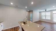 Located in Conroe, TX, this single-story, 3-bedroom, 2-bathroom home features a clean, contemporary design with neutral tones and warm wood-look flooring throughout the main living areas. The open-concept kitchen serves as a central hub, showcasing white shaker cabinetry, quartz countertops, a subway tile backsplash, stainless steel appliances, and a large center island with a built-in sink — ideal for both meal prep and casual dining. Recessed lighting illuminates the kitchen and living areas, creating a bright, welcoming atmosphere. The living area is generously sized, featuring a ceiling fan, natural light from blinds-covered windows, and direct access to the entry door with transom window above. Bedrooms are carpeted for comfort and include ample closet space with double-door closets featuring built-in rods and shelving. Both bathrooms are finished with white cabinetry, quartz countertops, and framed mirrors; the secondary bath includes a tiled tub-shower surround. The primary bath connects directly to the primary bedroom, which enjoys natural light and a neutral, restful color palette. Throughout, the home maintains a cohesive, move-in-ready aesthetic with consistent finishes and thoughtful design details.