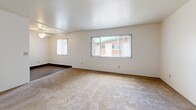 Located at 7844 Paradise Valley Road in San Diego, CA, this single-floor, 2-bedroom, 1-bathroom home offers a straightforward and functional layout. The living room is bright and open, featuring neutral carpet flooring, crisp white walls, and multiple windows fitted with vertical blinds that allow ample natural light to fill the space. A ceiling fan adds to the comfort of the primary bedroom, which also benefits from a window with views of surrounding greenery. The second bedroom is carpeted and well-proportioned, with a built-in shelving unit and a closet, providing useful storage options. Both bedrooms share clean, neutral tones and offer a calm, understated atmosphere. The combined dining room and kitchen area creates a convenient, open-plan space for everyday living. A hallway connects the main living areas to the bedrooms and the full bathroom, which features a soaking tub with a shower, stone-patterned surround walls with chrome fixtures, and wood-look flooring — offering a clean, functional design. Overall, the home presents a simple, well-maintained interior with a consistent neutral palette, making it a practical and adaptable living space in the Paradise Valley neighborhood of San Diego.