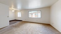 Located at 7844 Paradise Valley Road in San Diego, CA, this single-floor, 2-bedroom, 1-bathroom home offers a straightforward and functional layout. The living room is bright and open, featuring neutral carpet flooring, crisp white walls, and multiple windows fitted with vertical blinds that allow ample natural light to fill the space. A ceiling fan adds to the comfort of the primary bedroom, which also benefits from a window with views of surrounding greenery. The second bedroom is carpeted and well-proportioned, with a built-in shelving unit and a closet, providing useful storage options. Both bedrooms share clean, neutral tones and offer a calm, understated atmosphere. The combined dining room and kitchen area creates a convenient, open-plan space for everyday living. A hallway connects the main living areas to the bedrooms and the full bathroom, which features a soaking tub with a shower, stone-patterned surround walls with chrome fixtures, and wood-look flooring — offering a clean, functional design. Overall, the home presents a simple, well-maintained interior with a consistent neutral palette, making it a practical and adaptable living space in the Paradise Valley neighborhood of San Diego.