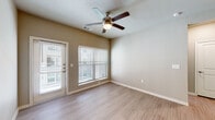 This single-floor residence offers a thoughtfully designed layout with a cohesive blend of modern finishes and practical features. The open living area is highlighted by light wood-look flooring, neutral warm-toned walls, and a ceiling fan with an integrated light fixture. Multiple windows dressed with horizontal blinds allow natural light to fill the space, while a glass-panel exterior door provides convenient outdoor access and additional brightness.

The kitchen is a standout feature, showcasing rich dark wood cabinetry, granite countertops, a classic white subway tile backsplash, and a full suite of stainless steel appliances including a side-by-side refrigerator with ice and water dispenser, an electric range, and a built-in microwave. A deep undermount stainless steel sink with a modern pull-down faucet anchors the countertop, and a pendant light adds a refined finishing touch.

The bedroom features plush wall-to-wall carpeting, a ceiling fan, and a window that invites natural light. An additional versatile room with wood-look flooring offers flexible use as an office or secondary bedroom. A built-in mudroom area with open shelving and hooks adds practical storage near the entry.

The bathroom is finished with granite countertops, a single undermount sink, and a tiled soaking tub and shower combination, rounding out this clean and functional space.