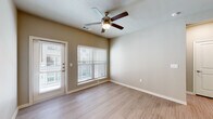 This single-floor residence offers a thoughtfully designed layout with a cohesive blend of modern finishes and practical features. The open living area is highlighted by light wood-look flooring, neutral warm-toned walls, and a ceiling fan with an integrated light fixture. Multiple windows dressed with horizontal blinds allow natural light to fill the space, while a glass-panel exterior door provides convenient outdoor access and additional brightness.

The kitchen is a standout feature, showcasing rich dark wood cabinetry, granite countertops, a classic white subway tile backsplash, and a full suite of stainless steel appliances including a side-by-side refrigerator with ice and water dispenser, an electric range, and a built-in microwave. A deep undermount stainless steel sink with a modern pull-down faucet anchors the countertop, and a pendant light adds a refined finishing touch.

The bedroom features plush wall-to-wall carpeting, a ceiling fan, and a window that invites natural light. An additional versatile room with wood-look flooring offers flexible use as an office or secondary bedroom. A built-in mudroom area with open shelving and hooks adds practical storage near the entry.

The bathroom is finished with granite countertops, a single undermount sink, and a tiled soaking tub and shower combination, rounding out this clean and functional space.