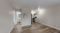 This single-floor residential unit offers a practical and clean layout designed for comfortable everyday living. Wood-look luxury vinyl plank flooring runs consistently throughout the space, providing a cohesive and low-maintenance aesthetic across all rooms.

The kitchen is efficiently arranged and features gray shaker-style cabinetry, a double-basin stainless steel sink, marble-look countertops, a white subway tile backsplash, and a stainless steel electric range, offering ample functionality for meal preparation.

The open living and dining area connects directly to the kitchen, creating a shared space that allows natural flow between daily activities. An electrical panel is conveniently recessed into the wall in this central zone.

The bedrooms are bright and well-proportioned, each featuring warm-toned neutral walls and natural light from windows fitted with horizontal blinds. Select bedrooms include wall-mounted air conditioning units and closet storage with bifold doors, offering practical organization solutions.

The bathroom is clean and straightforward, equipped with a white vanity, a full tub and shower combo with chrome fixtures, and a textured wall finish that adds subtle character.

Throughout the unit, neutral warm-beige walls, white trim, and consistent flooring create a unified, move-in-ready interior with a calm and functional ambiance.