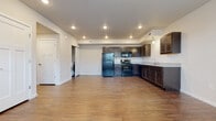 This single-floor unit is designed with a practical, open-concept layout that seamlessly connects the kitchen and living areas. Wood-look flooring runs consistently throughout the space, lending a cohesive and warm aesthetic to every room.

The kitchen is well-appointed with dark espresso-toned cabinetry offering generous upper and lower storage, light granite-style countertops, and a full suite of black appliances including a refrigerator, electric range, over-the-range microwave, and dishwasher. Recessed lighting illuminates the kitchen and open living area, which benefits from natural light provided by multiple windows fitted with horizontal blinds.

A dedicated in-unit laundry area is conveniently accessible from the main living space. The bedroom features wood-look flooring, a window for natural light, and a double sliding-door closet providing ample storage. The bathroom is finished with matching dark cabinetry, a granite-style countertop vanity, a large mirror with overhead lighting, and consistent wood-look flooring. A hallway connects the bedroom and bathroom, contributing to a functional and well-organized floor plan throughout the unit.