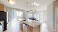 This single-floor unit at 146 Westgate Mall in Madison, Wisconsin, presents a clean, contemporary design characterized by a neutral color palette, light-toned luxury vinyl plank flooring, and an abundance of natural light throughout. A welcoming entryway corridor leads into the open-concept main living area, where the kitchen and living room flow seamlessly together.

The kitchen is well-appointed with light wood cabinetry extending to the ceiling, granite countertops, a large center island with an undermount sink and pendant lighting, and a full suite of stainless steel appliances including a French door refrigerator, electric range, built-in microwave, and dishwasher. A sliding glass door provides direct access to a balcony with outdoor views.

The living area is bright and airy, featuring large windows with horizontal blinds and a ceiling fan overhead. The bedroom offers plush carpeting, generous natural light from a sizeable window, and access to a walk-in closet. Two bathrooms are finished with granite-topped vanities and tile surrounds — one featuring a glass-enclosed shower. The overall ambiance is modern, calm, and functional.