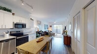 This well-appointed one-bedroom residence at Zona Apartments in Davie, Florida offers a thoughtfully designed open-concept layout that seamlessly connects the kitchen, dining, and living areas. The kitchen is a standout feature, showcasing crisp white cabinetry, gleaming granite countertops, stainless steel appliances including a refrigerator, electric range, microwave, and dishwasher, as well as track lighting overhead and durable wood-look flooring that flows throughout the main living spaces. The dining area provides a natural transition between the kitchen and the bright, airy living room, which is anchored by a ceiling fan and sliding glass doors that open to a private balcony with outdoor views — filling the space with abundant natural light. The bedroom is a serene retreat, featuring a ceiling fan, a window with natural light, and wood-look flooring. The bathroom is finished with large-format tile, a soaking tub and shower combination, granite vanity countertop, and white cabinetry. Clean white walls and contemporary finishes give the entire residence a modern, cohesive aesthetic, making it a comfortable and inviting place to call home in South Florida.