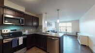Located at 1411 E 105th St in Cleveland, Ohio, this well-appointed single-floor residential unit offers a thoughtfully designed open-concept layout that seamlessly connects the kitchen, dining, and living areas. The kitchen is a standout feature, showcasing rich dark-espresso cabinetry, granite countertops, a subway tile backsplash, and a full suite of stainless steel appliances including a range, over-the-range microwave, dishwasher, and refrigerator. Pendant lighting above the peninsula adds a polished touch, while wood-look flooring runs throughout the main living areas, adding warmth and continuity.

The living space is bright and inviting, with large windows offering views of the surrounding treeline, allowing generous natural light to fill the room. A dedicated dining nook with oversized windows further enhances the airy feel of the space.

Both bedrooms are comfortably sized, each featuring natural light from well-placed windows and wood-look flooring. The bathroom is designed with dual vanities, granite countertops, and matching dark cabinetry, providing ample storage and a cohesive aesthetic that ties the entire unit together.