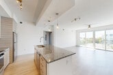 Located at 1402 S Dixie Hwy in Lantana, Florida, this modern 3-bedroom, 1-bathroom residence offers a thoughtfully designed single-floor layout with a bright, open feel throughout. Light wood-tone flooring flows seamlessly across the living areas, complementing the clean white walls and contemporary finishes.

The heart of the home is the open-concept kitchen and living area. The kitchen features a large center island with a granite countertop and an undermount sink, paired with two-tone cabinetry in white and warm wood grain. A full suite of stainless steel appliances — including a refrigerator, range, and microwave — adds a polished, functional touch. Pendant lighting above the island and track lighting throughout enhance the modern aesthetic.

The spacious living room is bathed in natural light from large sliding glass doors that open to a private balcony, offering views of the surrounding landscape. A ceiling fan keeps the space comfortable in Florida's warm climate.

The three bedrooms are well-proportioned, with the primary bedroom offering generous closet space. The bathroom is elegantly appointed with a granite vanity, wood-framed mirror, tile-surround tub and shower, and neutral porcelain floor tile. A dedicated laundry area and multiple closets throughout add practical storage to this well-appointed residence.