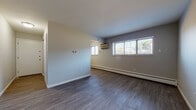 Located at 111 S Waverly Rd in Lansing, Michigan, this single-floor unit offers a clean, updated interior designed for functional everyday living. The layout, as seen in the floor plan, includes a spacious main living area, separate rooms, a kitchen, and a bathroom, all arranged in a practical configuration.

The living area is generously sized, featuring dark gray vinyl plank flooring that extends throughout most of the unit. Neutral-toned walls provide a versatile backdrop, while multiple windows fitted with horizontal blinds allow natural light to fill the space. A wall-mounted air conditioning unit and baseboard heaters ensure year-round climate control.

The additional rooms mirror the same flooring and neutral palette, each equipped with baseboard heating and windows that bring in natural light, offering flexible use as bedrooms or office space.

The kitchen is outfitted with dark espresso cabinetry paired with light granite-style countertops, a double-basin sink, and a range hood. Wood-tone vinyl flooring and a window contribute to a bright, functional workspace with ample storage.

The bathroom features wood-look vinyl flooring, a full soaking tub, and a tiled shower surround with a classic rectangular tile pattern, complemented by clean white fixtures throughout.