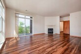 This single-floor, 3-bedroom, 2-bathroom residence offers a well-organized layout designed for comfortable everyday living. Rich hardwood flooring flows throughout the main living areas, beginning at the entry hallway that leads naturally into the open-concept kitchen and living room. The kitchen serves as a central hub, featuring a large island with granite countertops and a built-in sink, warm wood cabinetry, stainless steel appliances, and stylish pendant lighting overhead. Large windows along the exterior wall flood the space with generous natural light and provide views of the surrounding greenery. The adjoining living room is bright and airy, highlighted by a corner fireplace with a clean white mantle and direct access to an outdoor area via sliding glass doors. The primary bedroom is a comfortable, well-proportioned retreat with a ceiling fan, multiple windows offering outdoor views, and plush carpeting. Additional bedrooms are carpeted and offer practical closet storage with wire shelving systems. The two bathrooms are cleanly finished, with one featuring tile flooring, a walk-in shower, and wood-toned cabinetry. Two hallways and two closets round out the layout, offering convenient storage and connectivity throughout the home.