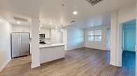 Located in Santa Clarita, CA, this well-appointed 2-bedroom, 2-bathroom residence offers a thoughtfully designed single-floor layout. The open-concept living and kitchen area serves as the heart of the home, featuring warm wood-style flooring that extends throughout. The modern kitchen is equipped with stainless steel appliances—including a gas range, built-in microwave, and refrigerator—complemented by crisp white cabinetry, a clean white countertop, subway tile backsplash, and pendant lighting over the sink peninsula. The living area flows naturally from the kitchen and receives natural light through a window, creating a bright and airy atmosphere. The spacious primary bedroom offers a window with outdoor views and connects to a full bathroom featuring a long dual-sink vanity with white countertops, gold-toned hardware, a soaking tub, and a dedicated walk-in closet with built-in shelving and hanging rods. The second bedroom is generously sized with its own window and direct access to the outdoors via a glass-paneled door. A second closet provides additional storage. The private covered balcony showcases charming arched architectural details, adding character to the exterior. Recessed lighting and neutral tones throughout create a clean, contemporary aesthetic.