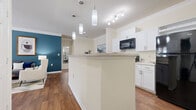 Located at 100 Madison Pl Cir in Kernersville, NC, this well-designed 2-bedroom, 2-bathroom residence offers a thoughtful single-floor layout. The open-concept living area connects the kitchen, dining room, and living room seamlessly. The kitchen features crisp white cabinetry, granite-style countertops, a peninsula with pendant lighting, and black appliances including a built-in microwave. Crown molding and hardwood-style flooring add a refined touch throughout the common areas. The dining area is a defined yet open space with crown molding detail, ideal for entertaining. The living room is bright and functional, with ample wall space. Both bedrooms are carpeted and feature large windows that invite natural light, with the primary bedroom offering a bold accent wall and generous proportions. Each bathroom is finished with white shaker-style cabinetry, stone-topped vanities, and hardwood-style flooring. A dedicated in-unit laundry area houses a full-size side-by-side washer and dryer. Two closets provide additional storage throughout the residence. The overall design balances modern finishes with a warm, comfortable ambiance.