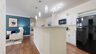 Located at 100 Madison Pl Cir in Kernersville, NC, this well-designed 2-bedroom, 2-bathroom residence offers a thoughtful single-floor layout. The open-concept living area connects the kitchen, dining room, and living room seamlessly. The kitchen features crisp white cabinetry, granite-style countertops, a peninsula with pendant lighting, and black appliances including a built-in microwave. Crown molding and hardwood-style flooring add a refined touch throughout the common areas. The dining area is a defined yet open space with crown molding detail, ideal for entertaining. The living room is bright and functional, with ample wall space. Both bedrooms are carpeted and feature large windows that invite natural light, with the primary bedroom offering a bold accent wall and generous proportions. Each bathroom is finished with white shaker-style cabinetry, stone-topped vanities, and hardwood-style flooring. A dedicated in-unit laundry area houses a full-size side-by-side washer and dryer. Two closets provide additional storage throughout the residence. The overall design balances modern finishes with a warm, comfortable ambiance.