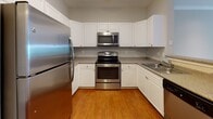 Located at 51 Cedar St in Woburn, MA, this single-floor residence offers a well-organized layout across several distinct living areas. The kitchen is equipped with stainless steel appliances, including a refrigerator, electric range, and over-the-range microwave, complemented by white cabinetry, granite-toned countertops, and warm hardwood flooring. A pass-through opening connects the kitchen to the living area, which features soft carpeting, crown molding, and track lighting overhead. The spacious living room opens toward French doors that introduce natural light and outdoor views.

The bedrooms are carpeted and finished with neutral gray walls and clean white trim, providing a calm, understated aesthetic. One bedroom includes access to a walk-in closet fitted with shelving and hanging storage. The bathroom is outfitted with light tile flooring, a white vanity with ample cabinet storage, a countertop sink, and a tub-shower combination with tiled surround. Throughout the unit, consistent neutral tones and clean finishes contribute to a cohesive, move-in-ready atmosphere suited for comfortable everyday living.