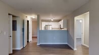 Located at 405 Thomas Burke Dr in Hillsborough, NC, this single-floor residence offers a well-designed open-concept layout with cohesive, modern finishes throughout. The living and dining area flows seamlessly toward the kitchen, which is defined by a raised peninsula with granite-style countertops and a cool blue-gray accent. The kitchen itself is equipped with stainless steel appliances, including a refrigerator, range, and over-the-range microwave, complemented by crisp white shaker cabinets, subway tile backsplash, and light stone countertops. Light wood-tone flooring runs throughout the main living spaces, lending warmth and continuity. The bedrooms are generously proportioned, each featuring ceiling fans and windows fitted with horizontal blinds that bring in natural light and views of surrounding greenery. Select bedrooms include closets with built-in shelving for organized storage. Two full bathrooms are finished in a clean, neutral palette, each with a tub-shower combination and wood-look flooring. Additional storage is accessible via a utility closet visible from the entry. The overall ambiance is bright, clean, and move-in ready, offering a comfortable and functional living environment in a convenient Hillsborough location.