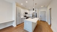 Located at 400 Universal Rd in Southern Pines, NC, this single-story 2-bedroom, 1-bathroom home offers a thoughtfully designed layout with clean, contemporary finishes throughout. Warm hardwood-style flooring flows consistently across all rooms, creating a cohesive and inviting atmosphere.

The kitchen serves as a standout centerpiece, featuring shaker-style cabinetry in soft grey and white tones, stainless steel appliances including a refrigerator, range, and built-in microwave, white quartz countertops, a deep undermount sink, and a large center island with pendant lighting — ideal for both meal prep and casual dining.

The living and dining areas are open and airy, with arched doorway details, ceiling fans, and natural light filtering in through window blinds. The primary bedroom is generously sized, offering ample space and direct access to a walk-in closet outfitted with wire shelving systems for organized storage.

The bathroom is finished with a glass-panel shower featuring matte black hardware and a built-in grab bar. A dedicated laundry room includes a top-load washer, wire shelving, and an electrical panel access point. A hallway connects all areas efficiently, completing this functional and modern single-floor layout.