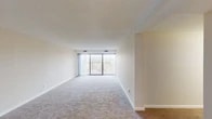 This single-floor residence offers a clean, functional layout designed for comfortable everyday living. The expansive living area is finished with plush wall-to-wall carpeting and features a textured ceiling, neutral walls, and a large sliding glass door that opens to a private balcony, flooding the space with natural light and providing views of the surrounding landscape. Vertical blinds offer adjustable light control throughout the day.

The kitchen is thoughtfully updated with white shaker-style cabinetry, granite countertops, a undermount sink, and a full suite of stainless steel appliances, including a refrigerator, range, microwave, and dishwasher. Light wood-look flooring ties the space together with a modern aesthetic.

The bedroom is generously sized, also featuring soft carpeting, a window with blinds for natural light, and a dedicated closet. The full bathroom is finished with granite countertops, white cabinetry, a medicine cabinet with mirror, wood-look flooring, and a full tub-shower combination.

A dedicated in-unit laundry area houses a full-size washer and dryer with overhead cabinetry for additional storage, adding a practical convenience to the home. Overall, the space presents a bright, neutral palette throughout.