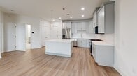This thoughtfully designed one-bedroom, one-bathroom residence at 300 Main Street in Madison, NJ offers a clean, modern aesthetic highlighted by light hardwood flooring and crisp white walls throughout. The open-concept layout seamlessly connects the kitchen, dining, and living areas into a single, cohesive entertaining space. The kitchen is a standout feature, equipped with soft gray shaker-style cabinetry, quartz countertops, a large center island, stainless steel appliances including a gas range, built-in microwave, and refrigerator, complemented by a herringbone tile backsplash and pendant lighting overhead. Recessed lighting adds a polished touch to the space. The living area benefits from natural light streaming in through large windows with blinds, creating a bright and welcoming ambiance. The bedroom is well-proportioned, offering windows on two sides for ample daylight and direct access to a walk-in closet with built-in shelving. The bathroom features a sleek gray vanity, large-format white tile flooring, and a sliding-glass-door tub and shower combination. Additional conveniences include in-unit laundry and three closets for generous storage throughout.