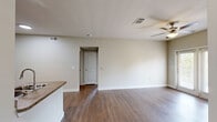 Located at 3 Vantage Way in Greenville, South Carolina, this one-bedroom, one-bathroom residence offers a well-organized single-floor layout designed for comfortable everyday living. The combined kitchen and living area forms the heart of the home, featuring durable hardwood-style flooring throughout. The kitchen is equipped with rich dark espresso cabinetry, granite-style countertops, a tile mosaic backsplash, black appliances including a refrigerator and range, a built-in microwave, and a peninsula with a double sink — ideal for both cooking and casual dining. The living area is bright and open, anchored by a ceiling fan and French doors that invite natural light and provide outdoor access. The bedroom is a comfortable, carpeted retreat with its own ceiling fan, a natural light-admitting window, and direct access to a walk-in closet outfitted with wire shelving for organized storage. The full bathroom features wood-toned cabinetry with granite-style countertops, a full tub-shower combination, and hardwood-style flooring. Neutral warm tones and clean finishes throughout lend the space a cohesive, move-in-ready aesthetic well-suited for residents seeking functional, low-maintenance living in Greenville, SC.
