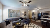 This two-bedroom, one-bathroom residence is thoughtfully designed across a single floor, offering a comfortable and cohesive living experience. The open-concept living and dining area is anchored by warm hardwood-style flooring, vaulted ceilings, and ceiling fans that enhance airflow and light throughout the space. Large windows bring in natural light, creating a bright and welcoming atmosphere.

The kitchen is well-equipped with dark wood cabinetry, light granite-style countertops, and black appliances including a refrigerator, range, microwave, and dishwasher. A peninsula with bar seating connects the kitchen to the dining area, making it ideal for casual dining and entertaining.

Both bedrooms are carpeted for comfort and feature windows with blinds for natural light and privacy. The primary bedroom includes ample closet space, while the second bedroom is equally versatile and well-sized. Ceiling fans are present in both rooms.

The bathroom offers a full tub and shower combination enclosed by sliding glass doors, complemented by dark wood cabinetry and hardwood-style flooring. The overall design palette of neutral tones and consistent finishes throughout creates a cohesive and modern aesthetic suited for everyday living.
