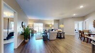 This single-floor residence offers a thoughtfully designed open-concept layout across a comfortable footprint, accommodating two bedrooms and two full bathrooms. The living room serves as the central gathering space, featuring warm wood-style flooring, neutral-toned walls, and a sliding glass door that fills the room with natural light and provides direct access to an outdoor patio area. The open flow connects seamlessly to the kitchen, which is well-equipped with two-tone cabinetry—white upper cabinets paired with dark lower cabinets—granite countertops, stainless steel appliances, pendant lighting, and a central island with bar seating, ideal for casual dining or entertaining.

The primary bedroom is a generously sized retreat with vaulted ceiling accents, soft neutral walls, and hardwood-style flooring. The second bedroom offers comparable finishes and ample space. Both bathrooms mirror the kitchen's design aesthetic, featuring granite-topped dark vanities, large mirrors, and a shower-tub combination. Throughout the residence, consistent use of wood-style flooring, neutral warm tones, and modern fixtures creates a cohesive and inviting ambiance.