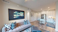 Located in Orlando's vibrant Ivanhoe Village neighborhood, this thoughtfully designed one-bedroom, two-bathroom residence offers a modern open-concept layout that maximizes every inch of its well-appointed floor plan. Rich wood-look flooring flows throughout the main living areas, tying the spaces together seamlessly.

The kitchen is a standout feature, outfitted with crisp white cabinetry, a marble-style tile backsplash, stainless steel appliances including a French-door refrigerator, and generous counter space. A movable island with a neutral countertop provides additional prep space and casual seating.

The living room is bright and welcoming, anchored by a ceiling fan and floor-to-ceiling glass doors that open to a private balcony with outdoor views. Recessed lighting and neutral wall tones create a clean, contemporary ambiance throughout.

The bedroom offers a cozy retreat with carpeted flooring, a large window with outdoor views, and dedicated closet space. The primary bathroom features wood-look tile flooring, a glass-enclosed walk-in shower with white subway tile, and a white vanity with ample storage. A second full bathroom adds convenience for guests.

The dedicated entrance and closet round out this efficiently designed single-floor residence, ideal for comfortable urban living.