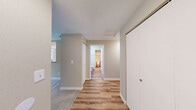 Located on Lawn Court in Tacoma, WA, this 2-bedroom, 2-bathroom residence offers a practical and comfortable single-floor layout. The living room serves as the heart of the home, anchored by a tile-surround wood-burning fireplace and sliding glass doors that open onto a private balcony overlooking lush greenery, filling the space with natural light. Warm wood-look plank flooring runs through the main living areas and hallways, while plush carpet provides comfort in the bedrooms. The kitchen features white cabinetry with modern hardware, stone-look laminate countertops, a peninsula for additional prep space, and a full suite of white appliances including an electric range and refrigerator. A hallway connects the two well-sized bedrooms, each offering neutral tones and carpeted floors. The primary bedroom benefits from a window with views of surrounding trees. Both bathrooms are finished with wood-look flooring, white vanities with stone-look countertops, and full tub-shower combinations. A dedicated closet provides additional storage. The overall aesthetic is clean and neutral, with a consistent palette of warm beige tones and white trim throughout.