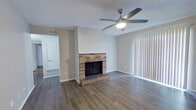 This single-story, 2-bedroom, 1-bathroom home offers a practical and comfortable floor plan across a compact yet efficient footprint. The living room serves as the centerpiece of the home, featuring a classic brick wood-burning fireplace, rich wood-look vinyl plank flooring, a ceiling fan with light, and a large sliding glass door dressed with vertical blinds that allows natural light to fill the space. Adjacent to the living area, the galley-style kitchen is equipped with white shaker cabinets, light countertops, a stainless steel sink, and stainless steel appliances, including a refrigerator and range, all set over matching vinyl plank flooring. The primary bedroom is generously sized and includes a ceiling fan, carpet flooring, and direct access to both the full bathroom and a dedicated walk-in closet outfitted with built-in shelving and hanging rods. The second bedroom also features carpet flooring, a ceiling fan with light, and a window with blinds providing natural light. The full bathroom includes a clean, white tub-shower combo. A hallway connects the private areas of the home, completing a straightforward and functional layout throughout.