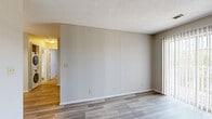 Located at 1890 N Lennox St in Olathe, Kansas, this two-bedroom, two-bathroom single-floor unit offers a practical and comfortable layout. The open-concept living, dining, and kitchen area serves as the heart of the home, with wood-style flooring flowing throughout the main spaces. The kitchen is equipped with warm honey-toned cabinetry, dark granite-style countertops, white appliances including a refrigerator, electric range, microwave, and dishwasher, and a breakfast bar that opens to the dining and living area. Track lighting illuminates the kitchen, while a sliding glass door in the living room welcomes natural light and outdoor access. Both bedrooms feature plush carpeting and ceiling fans, with the primary bedroom offering generous proportions and its own closet. Three closets throughout the unit provide ample storage. The bathrooms include a vanity with dark countertops, over-toilet cabinetry, and a shower-tub combination. A dedicated laundry area with a stacked washer and dryer adds everyday convenience. Textured ceilings and neutral wall tones give the space a clean, understated finish throughout.