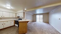 Located at 4529 Gull Prairie Pl in Kalamazoo, Michigan, this single-floor unit offers a practical and comfortable layout designed for everyday living. The open-concept kitchen and living area form the heart of the home, where a peninsula counter with warm oak cabinetry defines the kitchen space. White upper and lower cabinets provide generous storage, complemented by light countertops and a gas range. Wood-style flooring in the kitchen transitions seamlessly into the carpeted living area, which is bathed in natural light streaming through a large sliding glass door that opens to a private balcony overlooking the outdoors. A structural beam detail adds subtle architectural character to the ceiling above this shared space. The bedroom is generously proportioned, featuring plush carpet, neutral walls, and a pair of windows that bring in ample natural light and views of the surrounding neighborhood. Closet storage is conveniently accessible. The bathroom is finished with tile flooring and includes essential fixtures in a clean, functional layout. Throughout the unit, a neutral color palette of warm beiges and whites creates a calm, cohesive ambiance. The floor plan, as shown in the 3D model, is efficiently organized, with clear sightlines connecting the main living spaces.