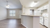 This 2-bedroom, 1-bathroom single-story unit offers a well-designed layout that maximizes functionality throughout. The open-concept living and dining area features vaulted ceilings and ceiling fans, creating an airy atmosphere enhanced by natural light from multiple windows with blinds. Wood-style plank flooring runs consistently throughout the unit, providing a cohesive and easy-to-maintain finish.

The kitchen is positioned at the heart of the home and features a peninsula with a light-toned countertop and an integrated sink, white cabinetry with ample storage, and white appliances including a refrigerator, electric range, and dishwasher. A pass-through window connects the kitchen to an adjacent area, improving sightlines and flow.

The primary bedroom offers a comfortable footprint with a ceiling fan and access to a spacious walk-in closet equipped with dual hanging rods and a built-in shelving unit. The second bedroom includes a ceiling fan and a window with exterior views. The bathroom is outfitted with a single-sink vanity featuring white cabinetry, a mirror, and a step-in shower/tub combination with grab bars. The unit also includes a dedicated entry area with a front door and adjacent closet, completing a practical and functional floor plan.